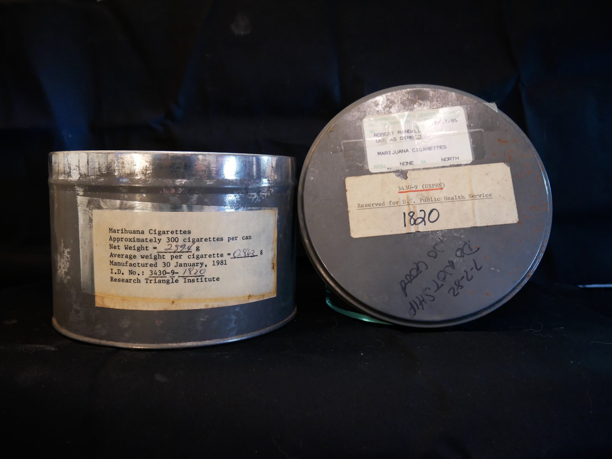 Labeled federal cannabis tins from Alice’s collection; the featured supply dates to December 1985.